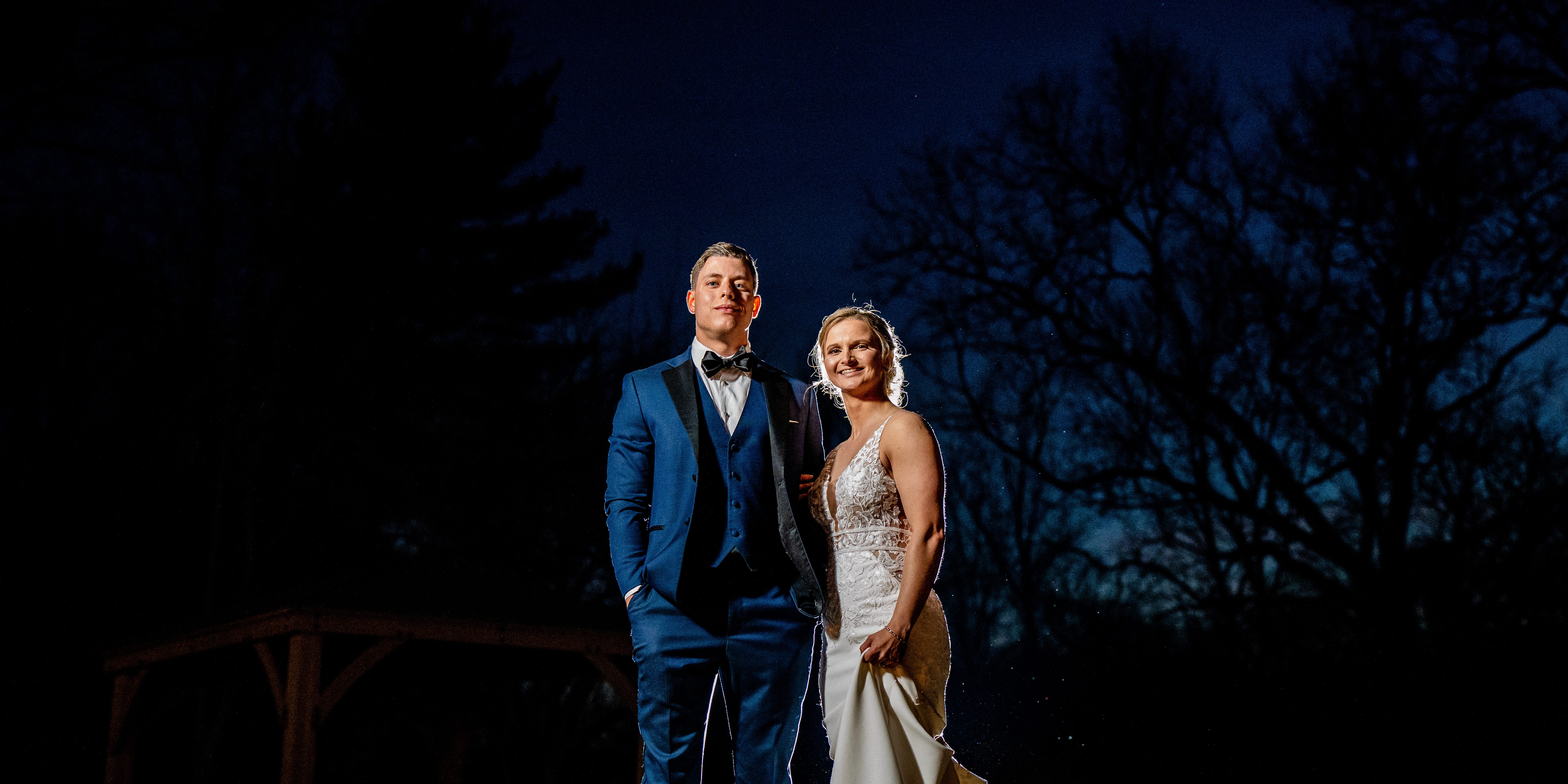 Bride and groom smiling at night by a gazebo at their Riverdale Manor wedding, surrounded by trees.