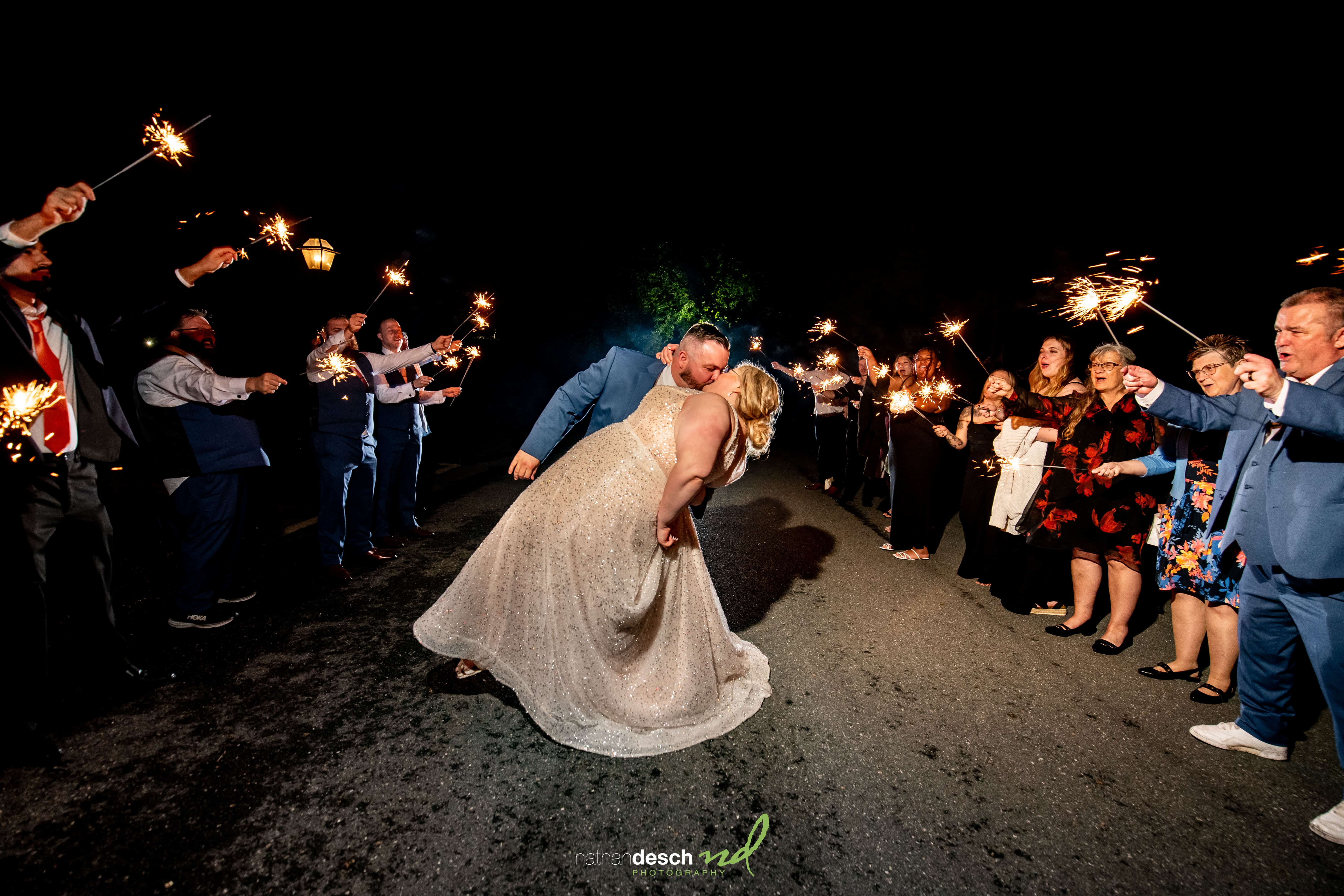 Bride and groom share a romantic kiss as guests hold sparklers at night at Drumore Estate spring wedding.