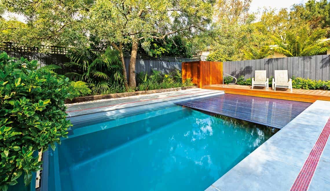 Northern Colorado Pools creates a relaxing backyard spot with a modern pool, comfy chairs, and private fenced space.