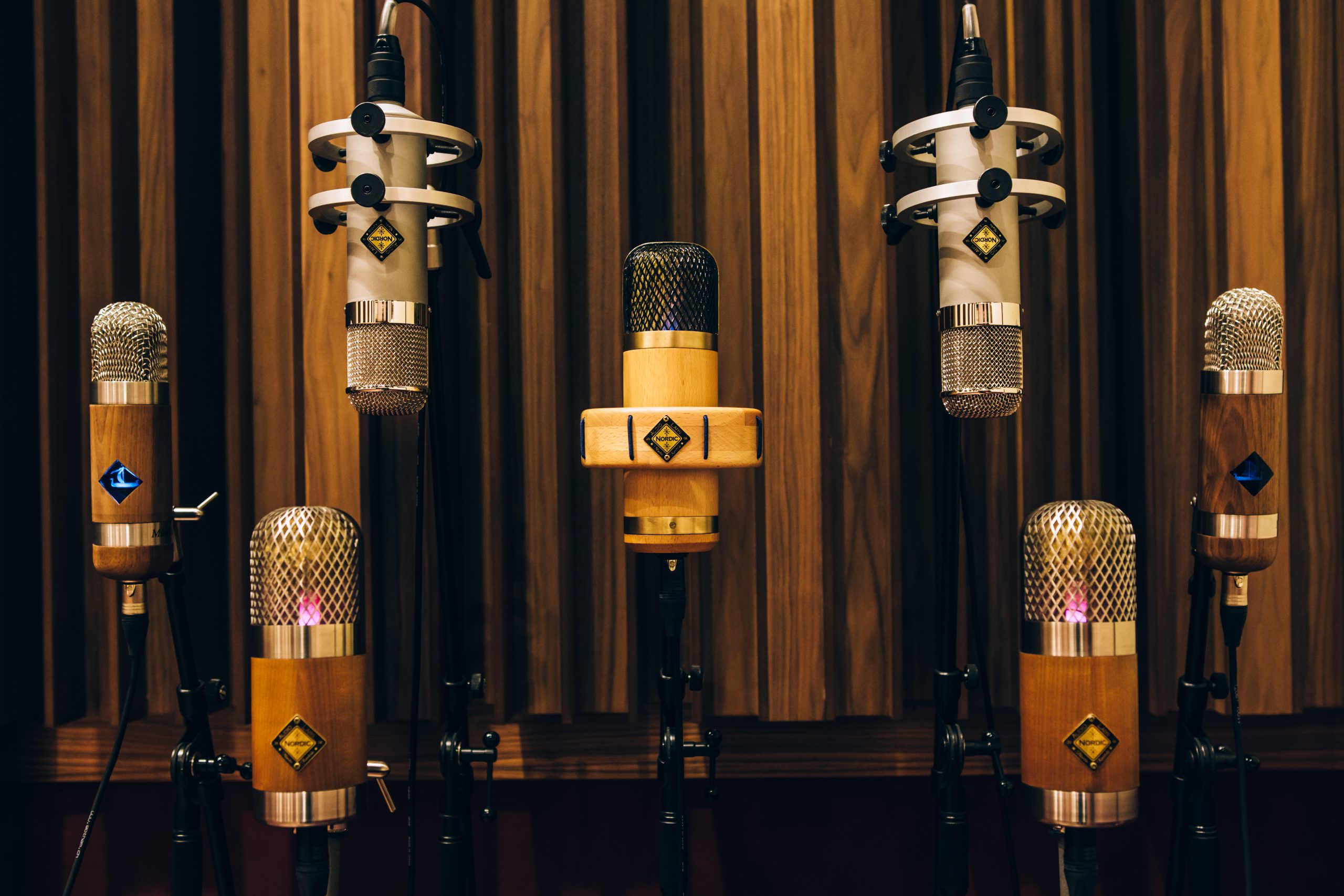 Collection of Nordic Audio Labs microphones displayed in a recording studio with wooden acoustic panels