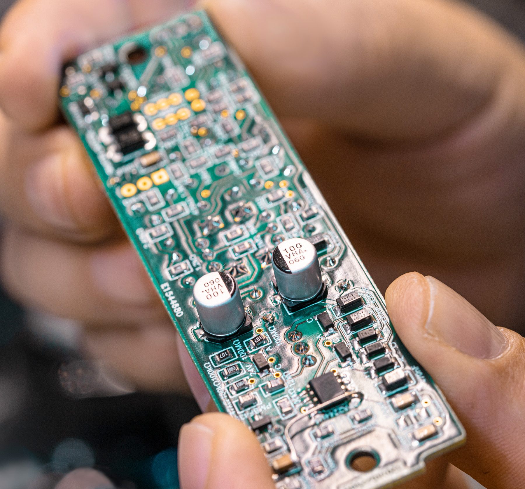 Close-up of a hand holding the internal circuit board of the NU-100K microphone