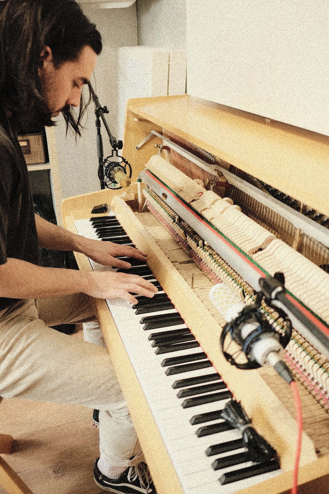 Manu Laudic playing upright piano with two NU-100K microphones positioned for recording