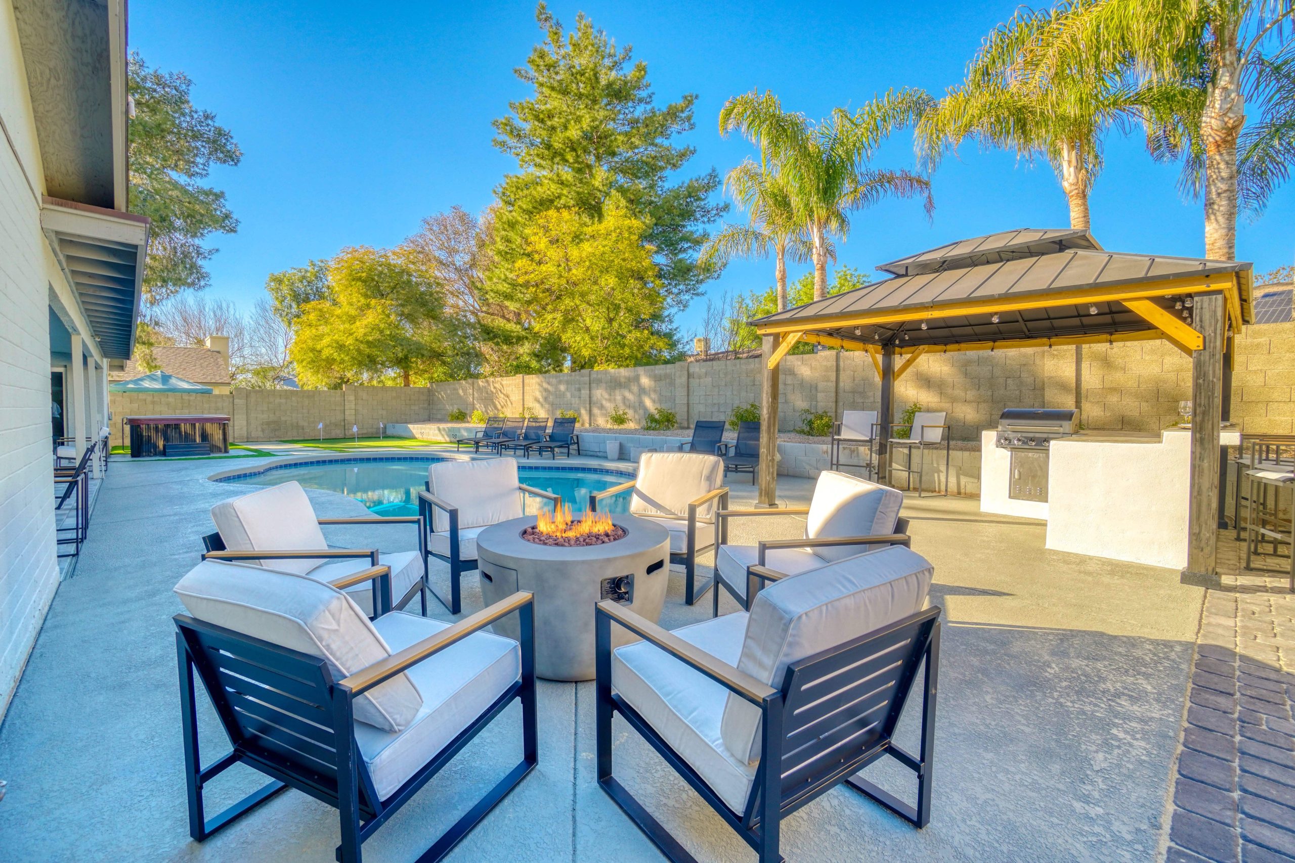 A roaring fire in an outdoor fire pit next to a swimming pool.