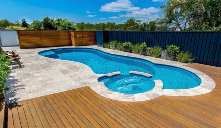 Custom fiberglass pool with a connected hot tub and large patio area