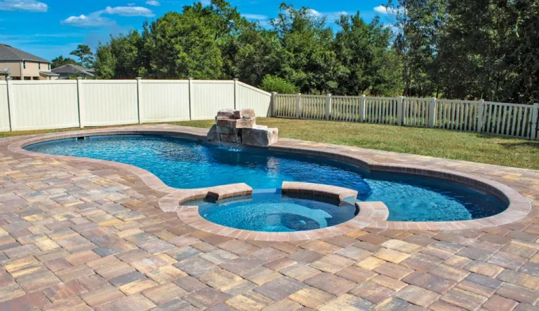 Custom fiberglass pool with a connected hot tub and natural stone waterfall feature
