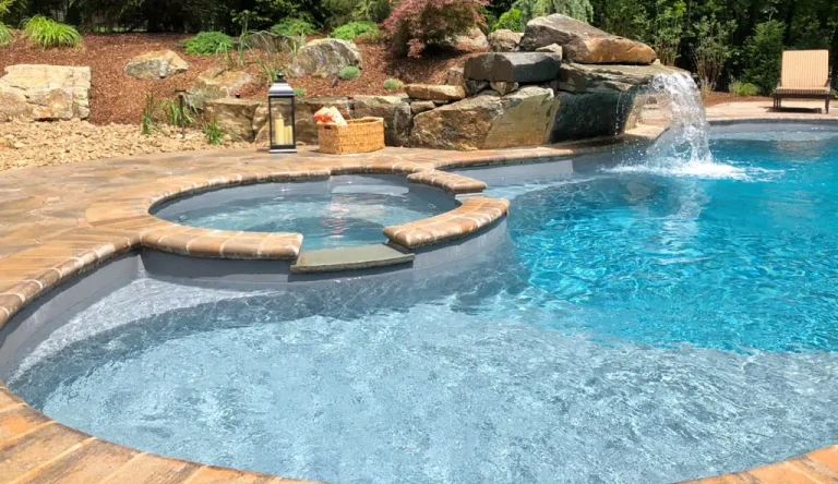 Custom fiberglass pool with a connected inground spa and natural stone waterfall feature