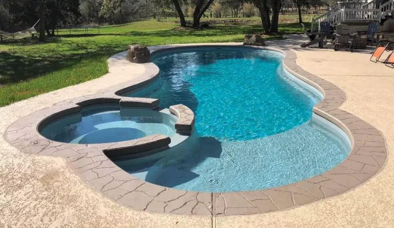 Free form fiberglass pool with a connected inground spa