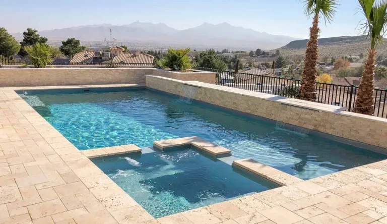 Rectangular swimming pool with three built-in steps across the water, surrounded by light stone tiles, palm trees, and a view of distant mountains under a clear sky—an inspiring choice for pool projects or luxurious concrete swimming pools.