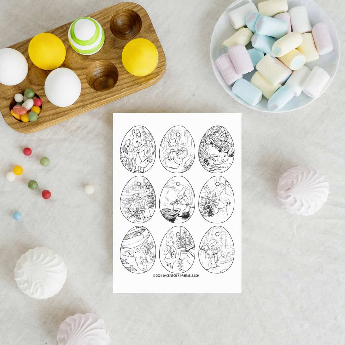 Peter rabbit and friends coloring ornaments laying on a table with eggs and candy.