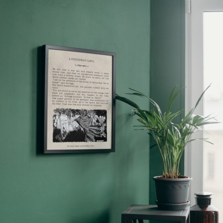 A Christmas Carol framed quote of Scrooge with the Ghost of Christmas future framed and displayed on a green wall.