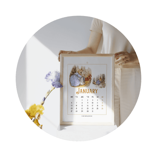 A woman's hands holding a framed calendar with Peter Rabbit illustrations.