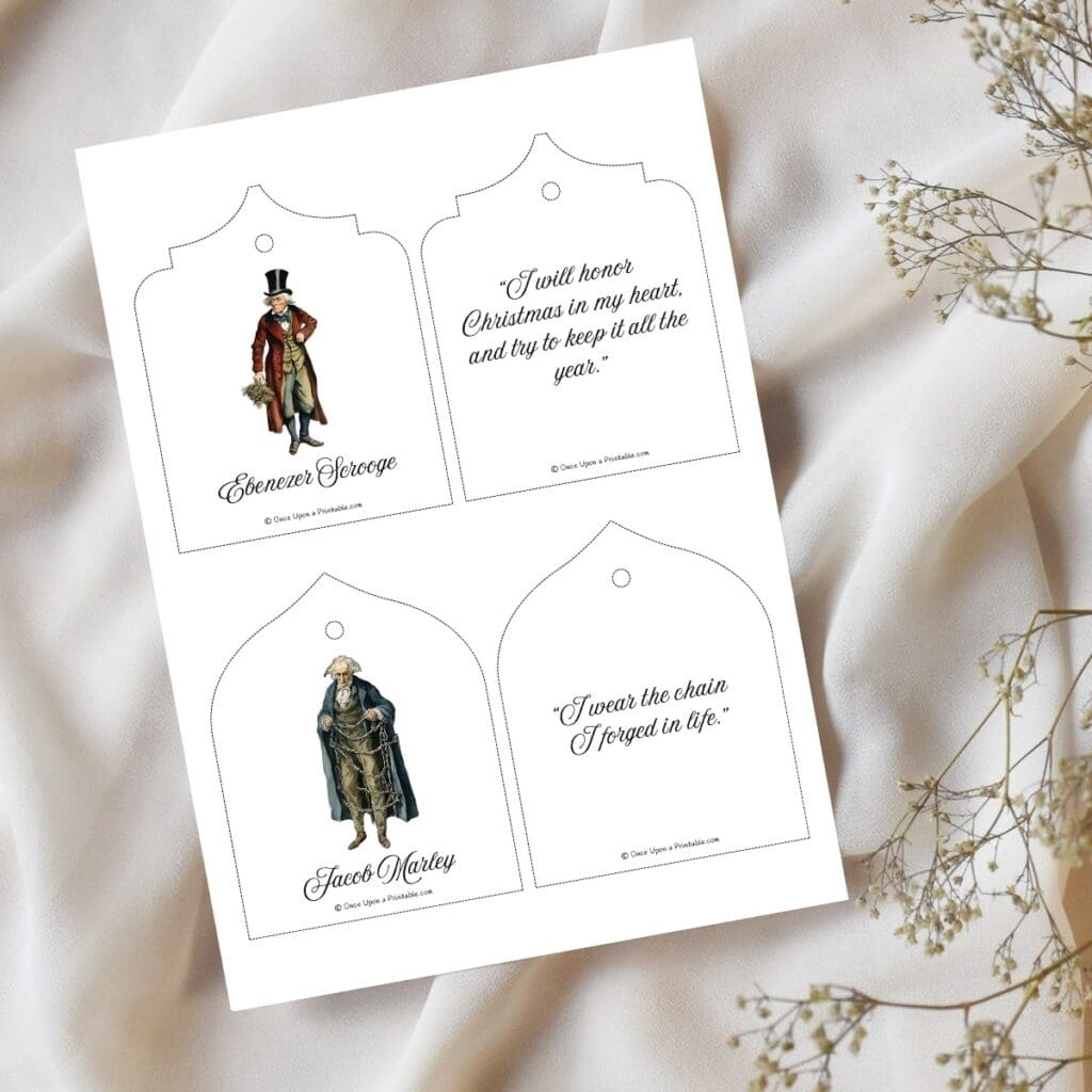 Scrooge and Marley printable christmas tree oranments page laying on a white table cloth with baby's breath.