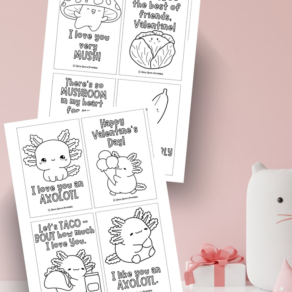 Mushroom and Axolotl Valentine's day Coloring cards laying on a pink background.