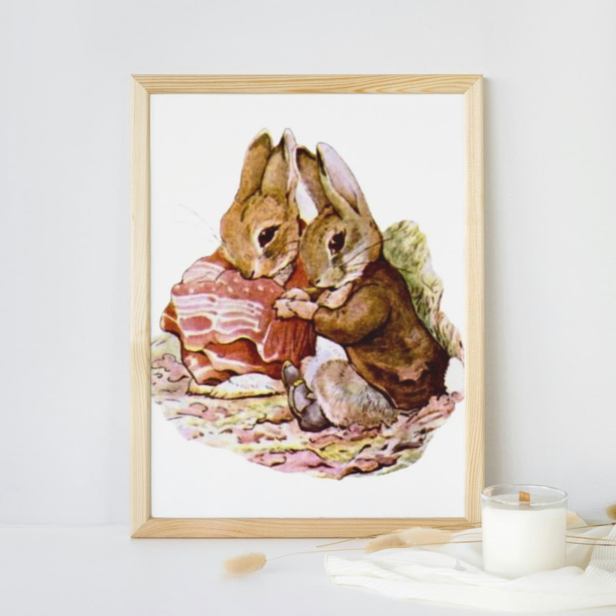 Benjamin Bunny and Peter Rabbit illustration framed and sitting on a table with a candle.