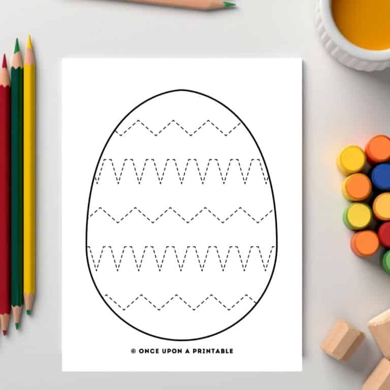 Easter egg tracing pages with zig zags laying on a table with coloring supplies.