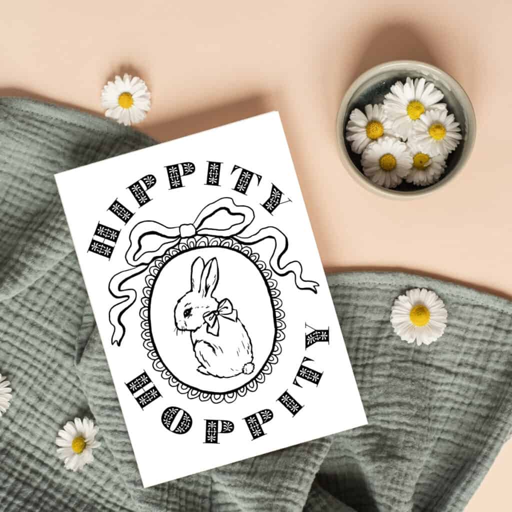 Happy Easter coloring card with a bunny rabbit with a bow laying on a green blanket with daisies.