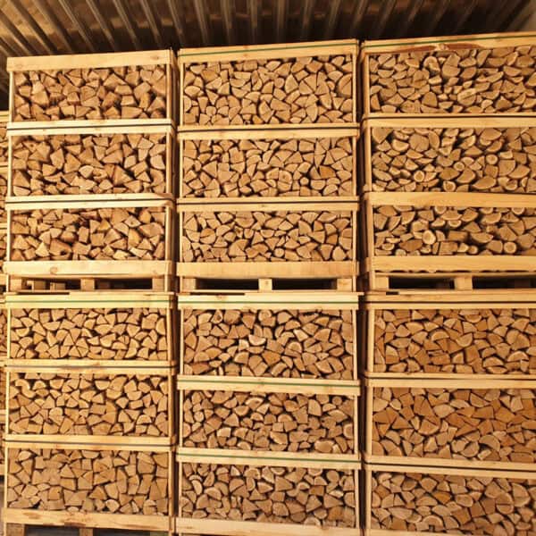 Stapels netjes gerangschikt brandhout worden vastgezet in Jumbopallet Ovengedroogd Mixhout kratten van Onshout.nl, in rijen geplaatst. Elke krat bevat gelijkmatig gezaagde houtblokken, ideaal voor gebruik binnenshuis.