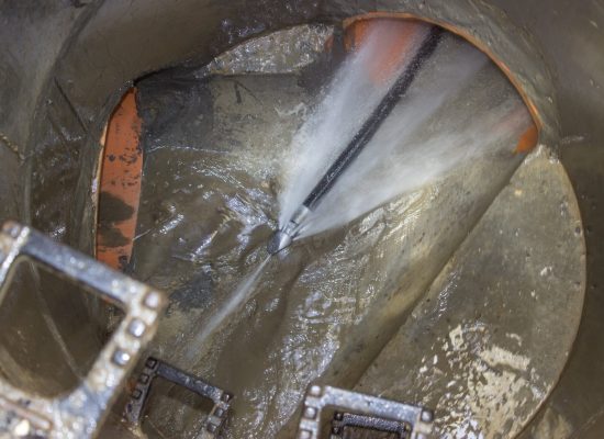 Technician performing hydro jetting to clear sewer line