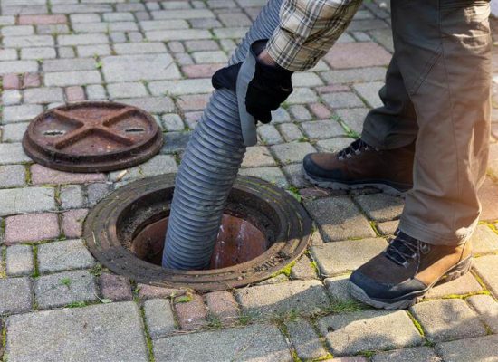 Technician performing routine sewer maintenance in residential area
