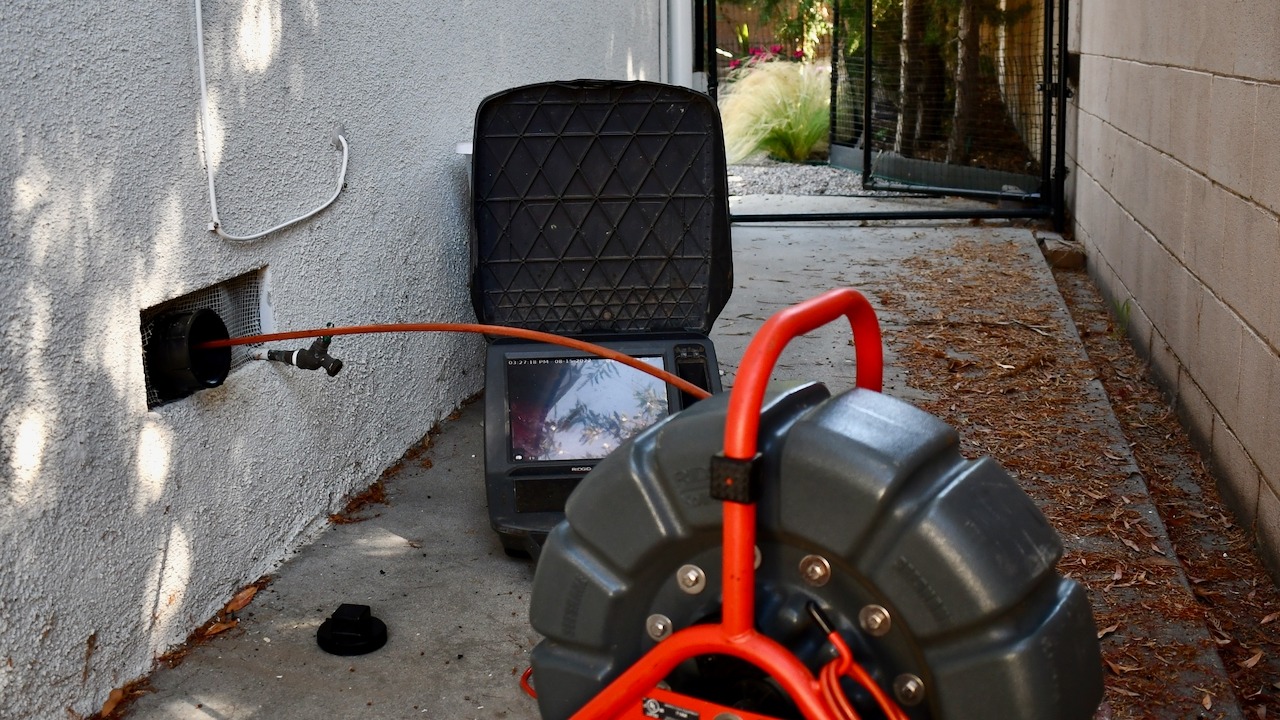 Prodigy Sewer and Drain uses a camera device to check the inside of a pipe near a building.