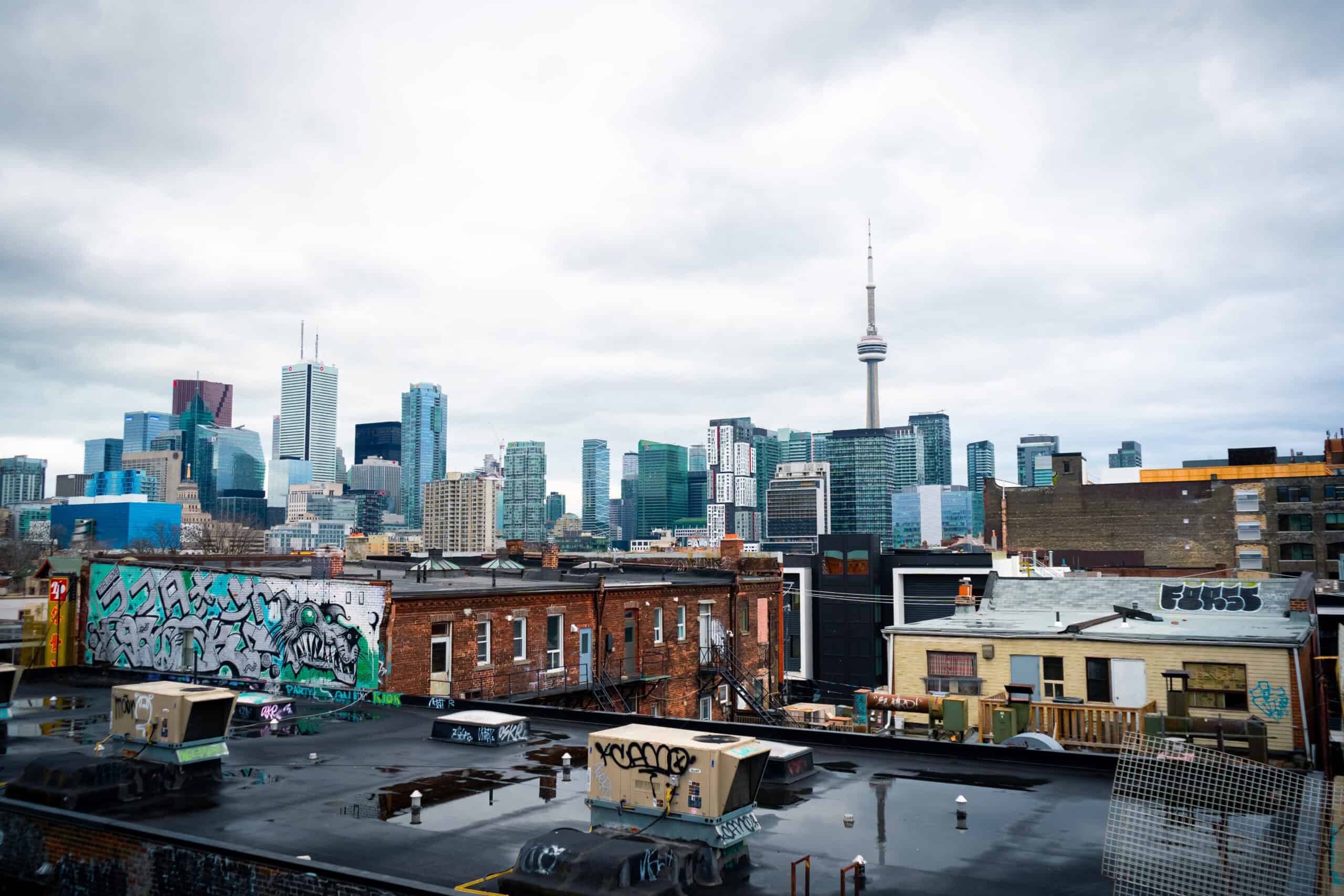 An image of the toronto skyline from the roof of a parking garage. The CN Tower is in the background with graffiti visible on the the buildings in the forefront