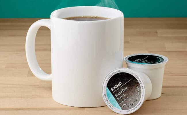White mug with coffee pods on table.