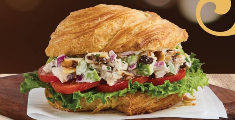 Chicken salad croissant sandwich with lettuce and tomato.