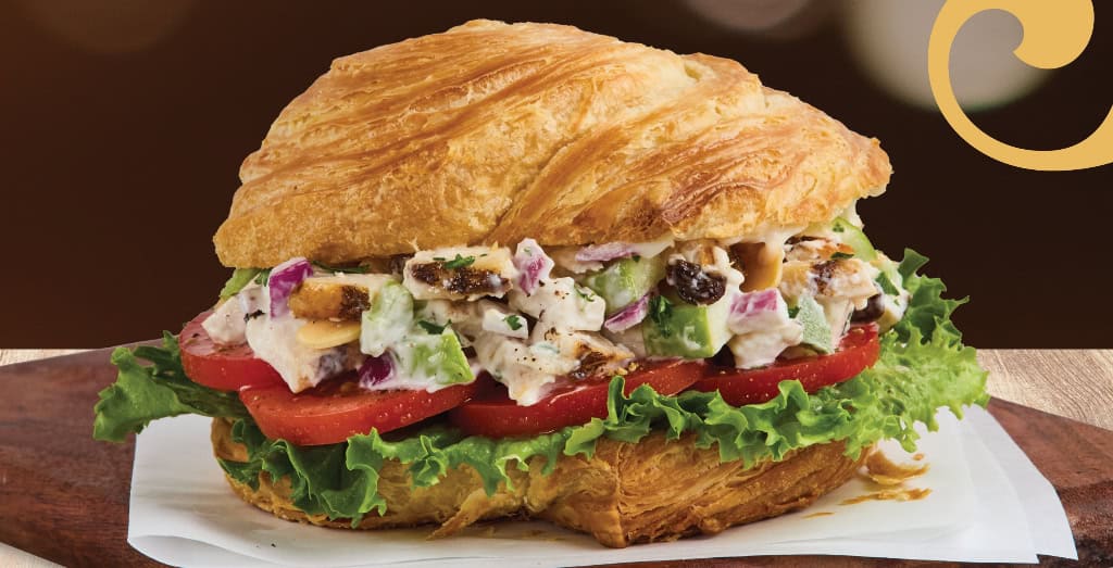 Chicken salad croissant sandwich with lettuce and tomato.