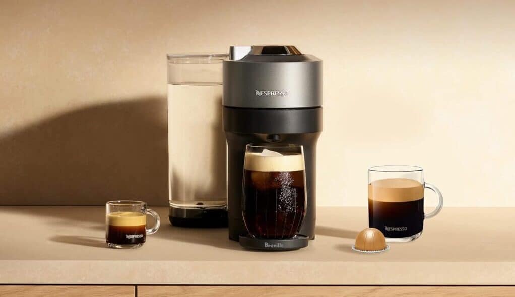 Nespresso coffee machine with cups and pods.