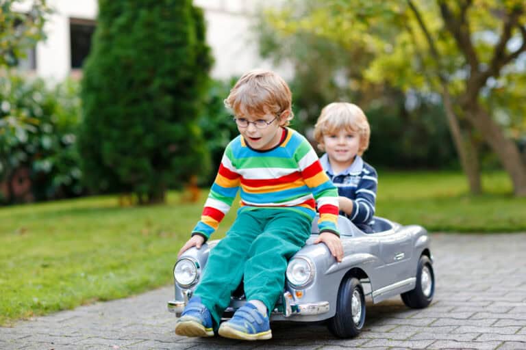 two little preschool boys playing with big old toy car in summer garden, outdoors. happy children play together, driving car. outdoor activity for kids. siblings and friends on warm day