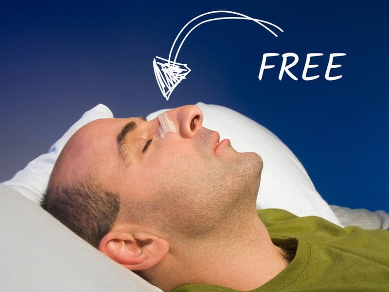Man sleeping with nasal strip, blue background.