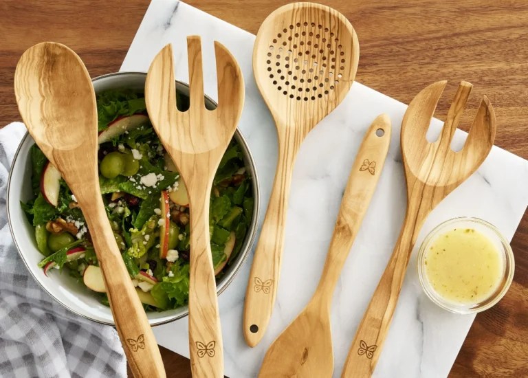 Wooden utensils and salad on marble surface.