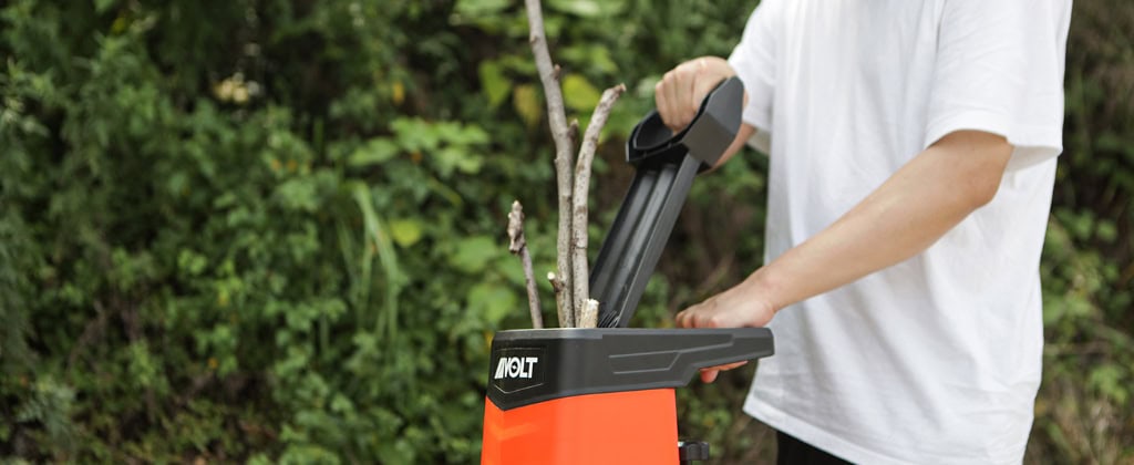 Person using wood chipper in garden