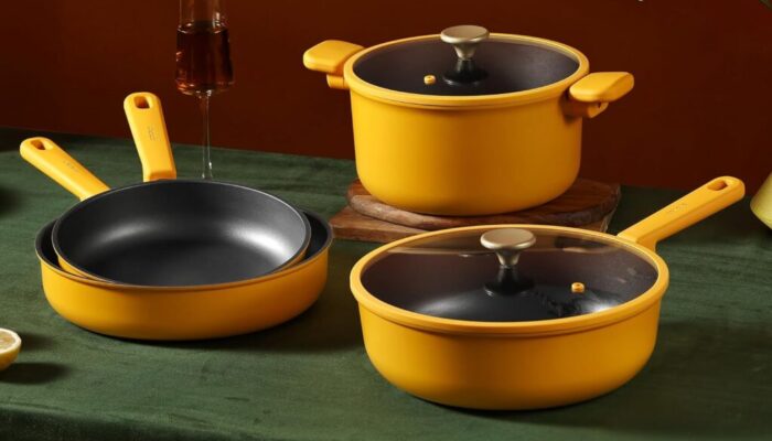 Yellow cookware set with lids on green table.