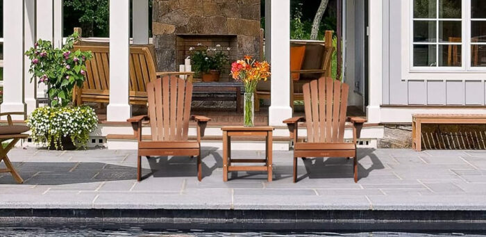 Patio with Adirondack chairs and flowers by poolside.
