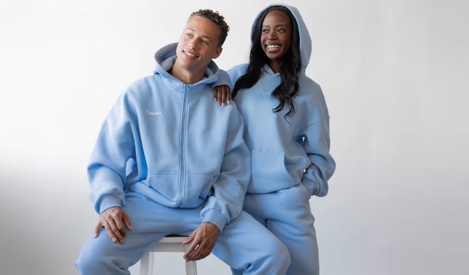 Two people in blue comfy sweatshirts smile.