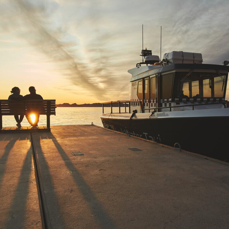 Two people watching the sunset waiting to board a water taxi