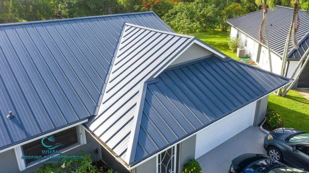 Metal Roof Replacement in Parkland 1 A house with a dark gray metal roof and white garage door, surrounded by green trees and parked cars in the driveway.