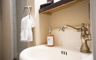 We offer eight guest rooms with queen beds and small ensuite baths. Some amenities include luxury bedding, flat-screen televisions, high-speed wireless internet, blackout shades, and our handcrafted Plainview Farm toiletries. We also provide filtered water and Nespresso makers in the kitchenette near the rooms and a small sitting area for reading or working. The kitchenette has a microwave, refrigerator drawer, and freezer drawer for use by guests. Nearby is a washer and dryer, also available for guest use.