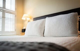 We offer eight guest rooms with queen beds and small ensuite baths. Some amenities include luxury bedding, flat-screen televisions, high-speed wireless internet, blackout shades, and our handcrafted Plainview Farm toiletries. We also provide filtered water and Nespresso makers in the kitchenette near the rooms and a small sitting area for reading or working. The kitchenette has a microwave, refrigerator drawer, and freezer drawer for use by guests. Nearby is a washer and dryer, also available for guest use.