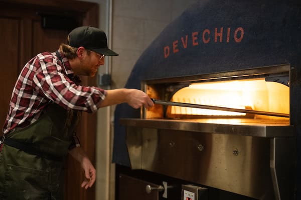 Chef placing pizza into Stone Hearth Oven at Mama DeVechio's Pizzeria
