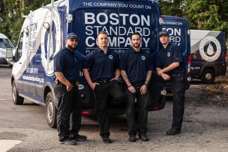 Four men in blue uniforms stand proudly in front of a Boston Standard Company van, exemplifying top-tier customer service as they prepare for their next assignment.