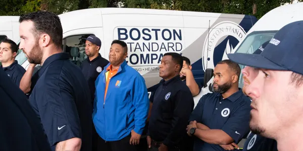 A group of men in uniform stand in front of a Boston Standard Company van, ready for their next Electrical Safety Inspection.