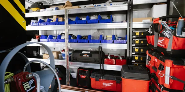 The interior of the service vehicle boasts organized shelves filled with tools and equipment essential for heating installation, alongside neatly arranged storage bins for easy access.