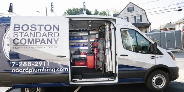 Open van with "Boston Standard Company" branding, showcasing plumbing tools and equipment alongside mini-split installation gear.
