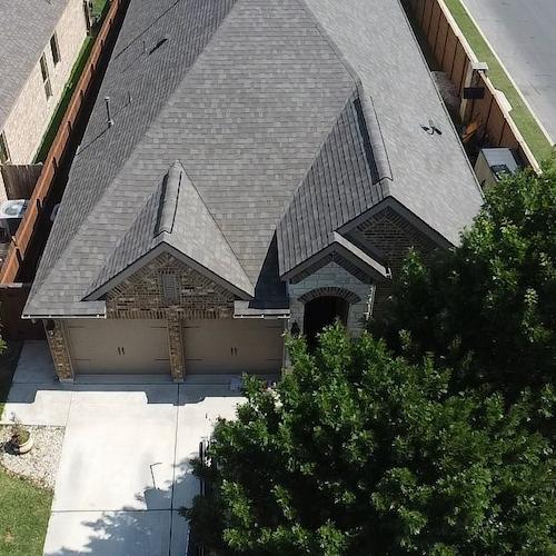Aerial drone view of residential roof showing damage for insurance claim by Dolan Roofing & Construction in San Antonio
