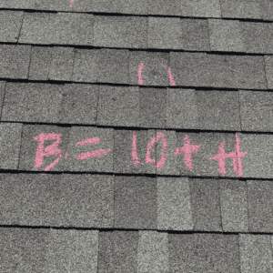 Asphalt shingle roof with a marking in pink spray paint for roof replacement in San Antonio, TX