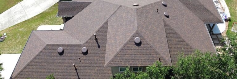 Aerial view of a house with a brown shingle roof installed by Dolan Roofing & Construction in San Antonio, TX