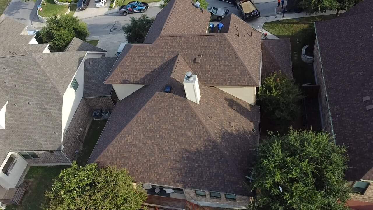 Aerial view of a house with a brown shingle roof installed by Dolan Roofing & Construction in San Antonio, TX
