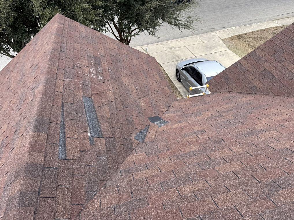 Storm-damaged roofing with visible cracks and missing shingles